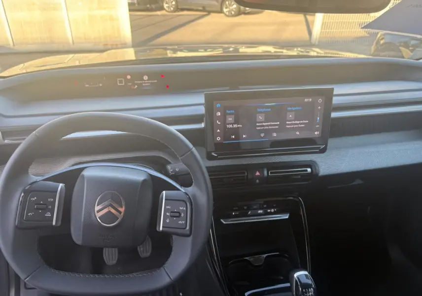 Vue intérieure du tableau de bord de la Citroën C3 2025 gris foncé, avec volant multifonction et écran tactile central.