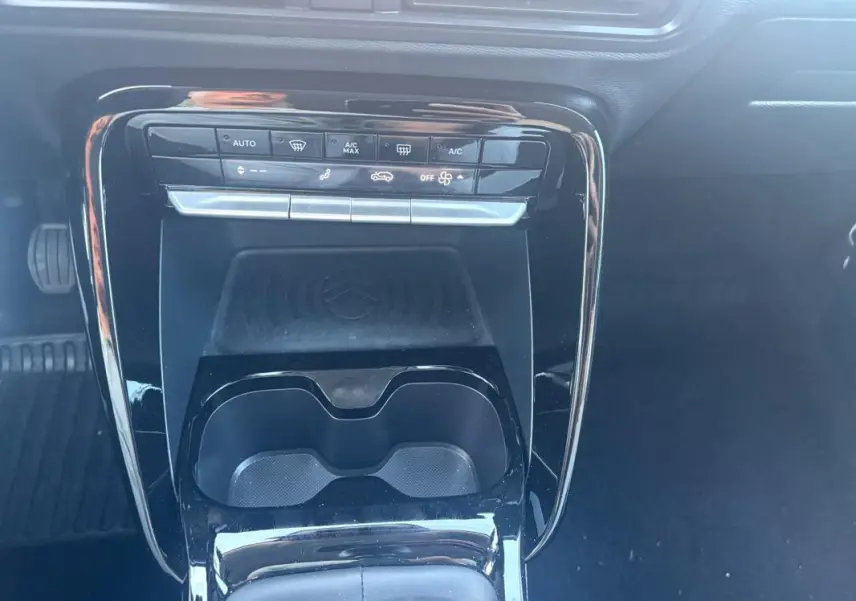 Vue rapprochée de la console centrale noire brillante du Citroën C3 2025, avec commandes climatisation et porte-gobelets.