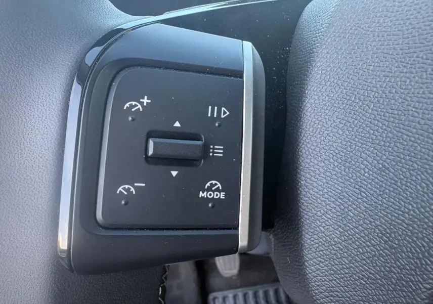 Gros plan sur les commandes au volant du Citroën C3 2025 gris foncé, avec réglages de vitesse et mode visible.
