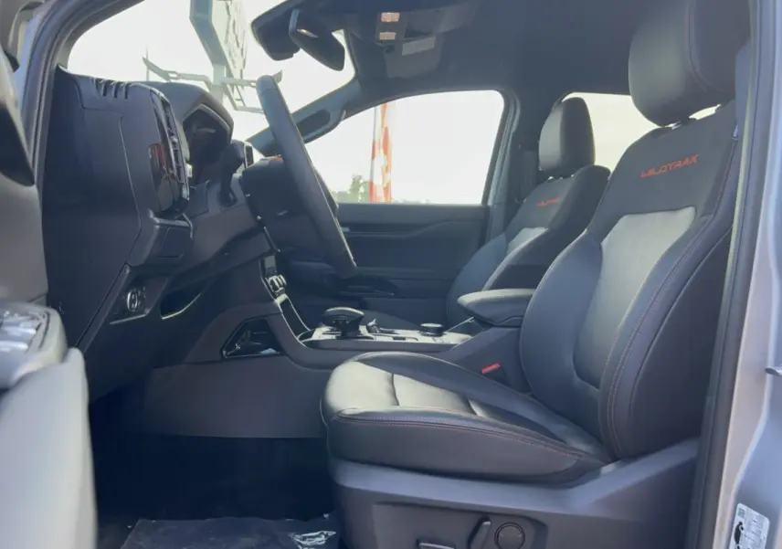 Vue intérieure côté conducteur du Ford Ranger Wildtrak 2026 avec sièges cuir noirs et surpiqûres orange WILDTRAK brodées.