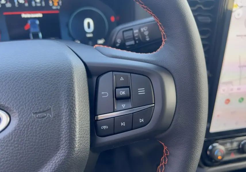 Gros plan sur les commandes multifonctions du volant en cuir noir avec surpiqûres rouges du Ford Ranger Wildtrak 2026.
