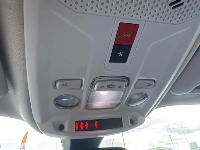 Vue intérieure du plafonnier de la Peugeot 2008 gris Artense avec commandes d’éclairage et bouton SOS rouge.