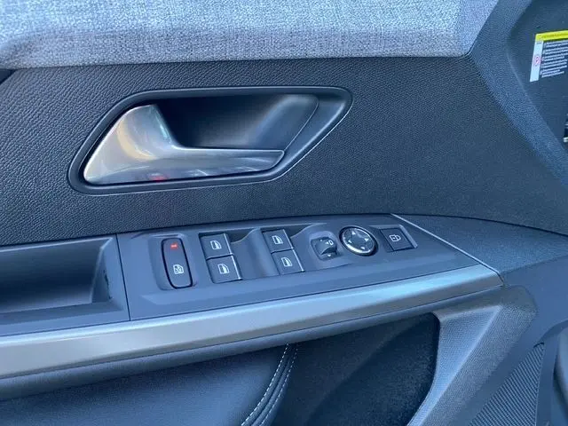 Détail de la porte côté gauche du Peugeot 5008 gris titane, avec commandes des vitres et poignée intérieure métallique.