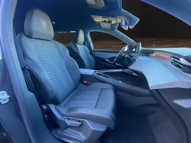 Vue intérieure côté gauche du Peugeot 5008 Hybrid 145 GT 2025, sièges gris noir avec logo Peugeot brodé.