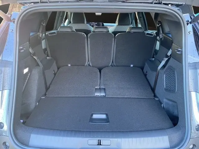 Coffre ouvert du Peugeot 5008 gris titane, vue arrière montrant les sièges arrière partiellement rabattus et l'espace de chargement.