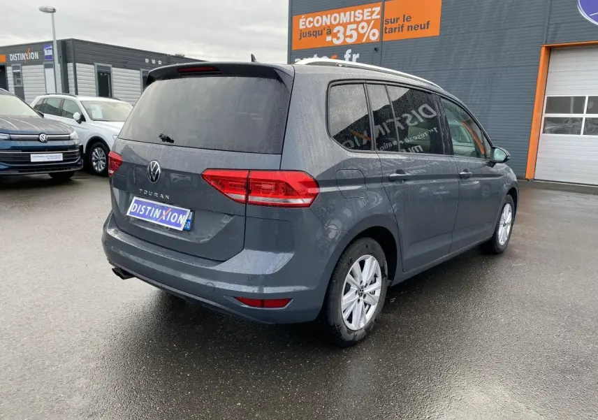 Vue 3/4 arrière droite d'un Volkswagen Touran gris dauphin avec vitres surteintées et jantes alliage 16 pouces.