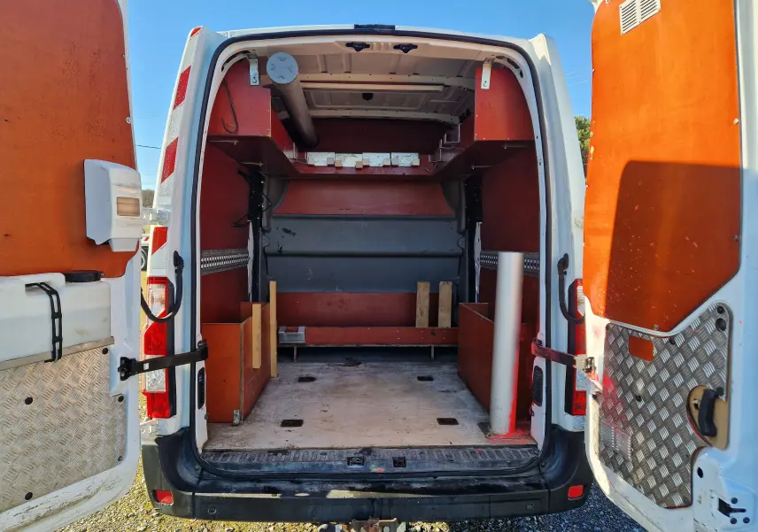 Vue arrière ouverte du Renault Master blanc L2H2 2019, montrant l'aménagement bois intérieur et les portes arrière ouvertes.