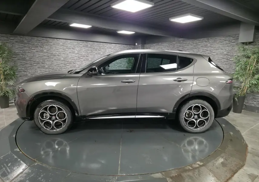 Vue de profil côté gauche de l'Alfa Romeo Tonale gris métallisé avec jantes alliage 18 pouces en showroom.