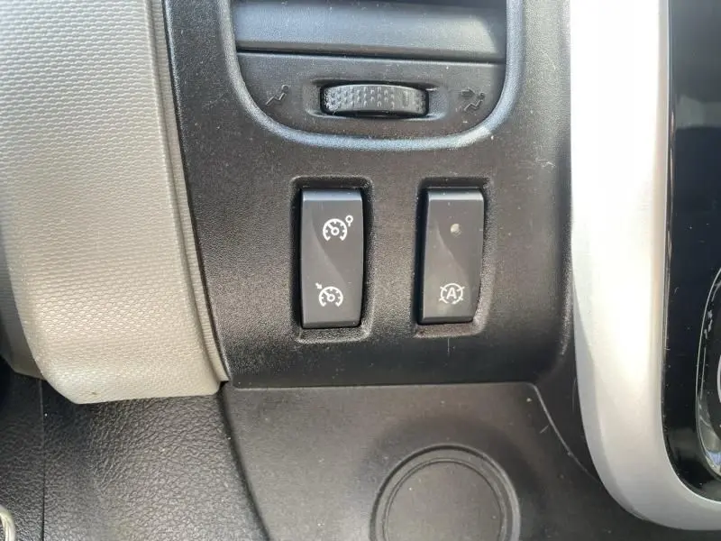 Gros plan sur les boutons de régulateur de vitesse et arrêt auto du moteur du Renault Trafic Fourgon blanc, version 2017.