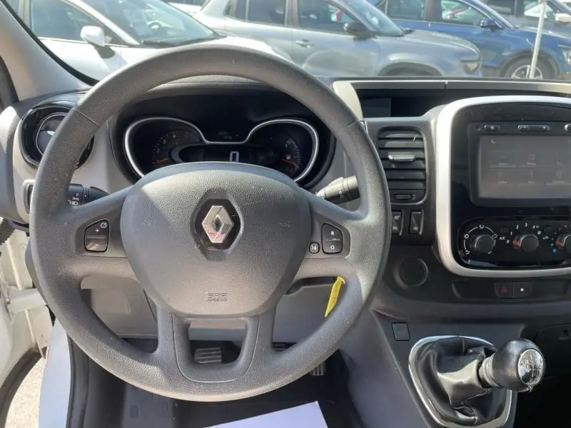 Vue intérieure centrée sur le volant et le tableau de bord du Renault Trafic Fourgon blanc, avec levier de vitesse manuel visible.