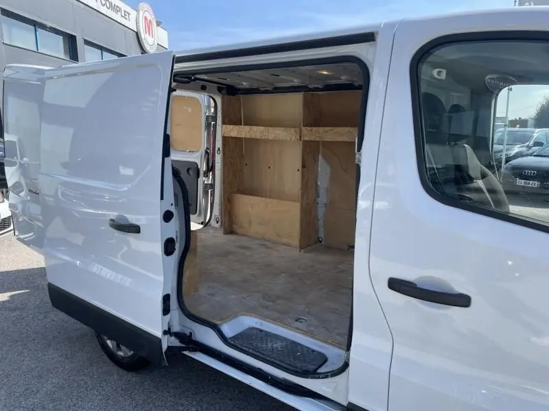 Vue latérale droite d’un Renault Trafic Fourgon blanc 2017 avec porte coulissante ouverte montrant l’intérieur vide en bois.