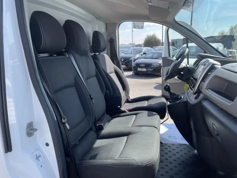 Vue intérieure côté conducteur du Renault Trafic fourgon blanc 2017, montrant les sièges noirs et la console centrale.