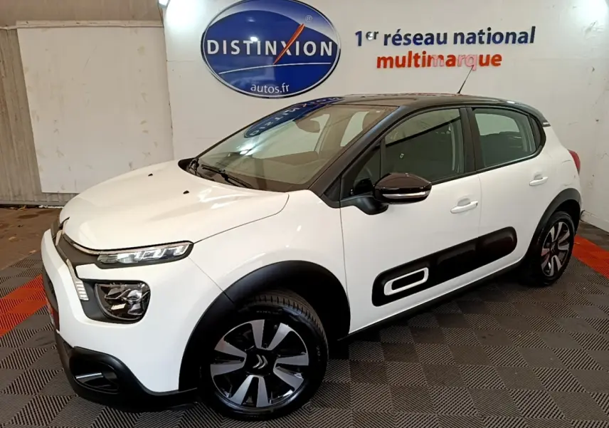 Citroën C3 blanche vue 3/4 avant droit, avec protections latérales noires et jantes alliage distinctives.