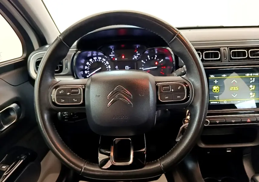 Vue intérieure centrée sur le volant cuir multifonctions d'une Citroën C3 2021 avec tableau de bord et écran tactile.