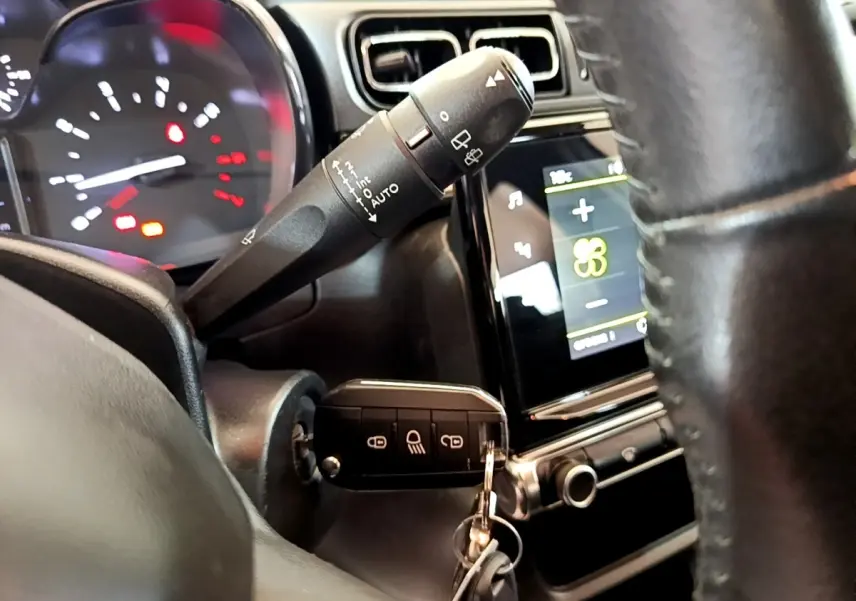 Vue rapprochée de l’intérieur de la Citroën C3 blanche, volant cuir et clé insérée dans le contacteur.