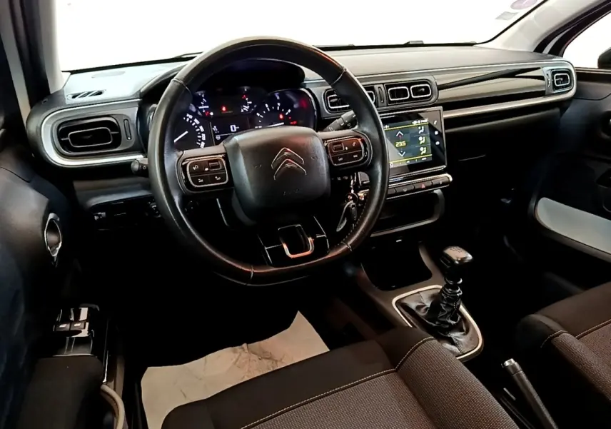 Intérieur noir de Citroën C3 2021, vue du poste de conduite avec volant cuir multifonctions et écran tactile central.