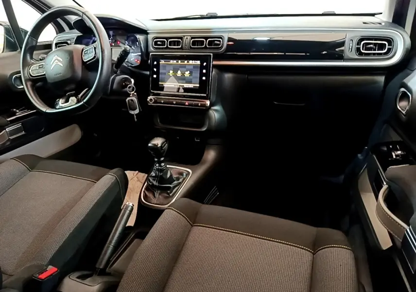 Vue intérieure avant droite du Citroën C3 blanc, montrant le volant cuir multifonctions et l’écran tactile central.