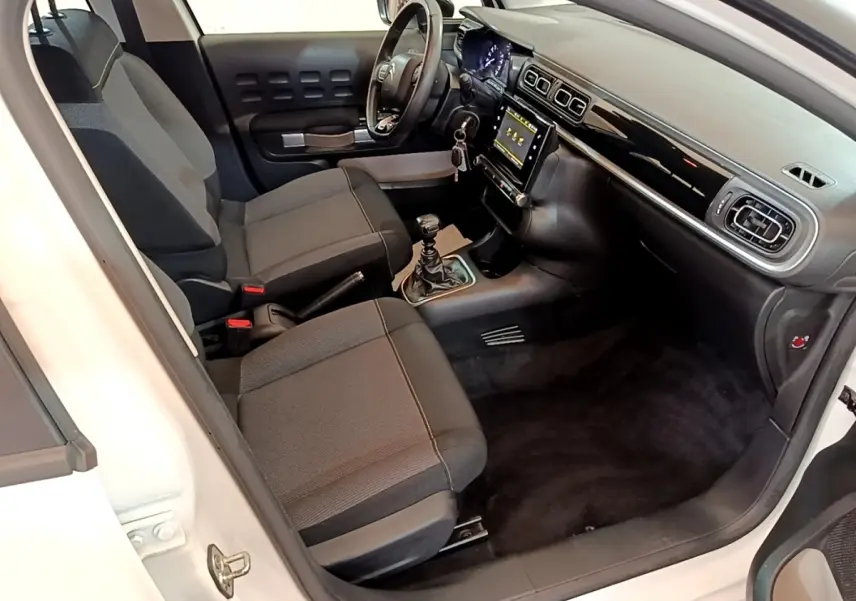 Vue intérieure côté conducteur de la Citroën C3 blanche 2021, volant cuir multifonctions et écran tactile central.