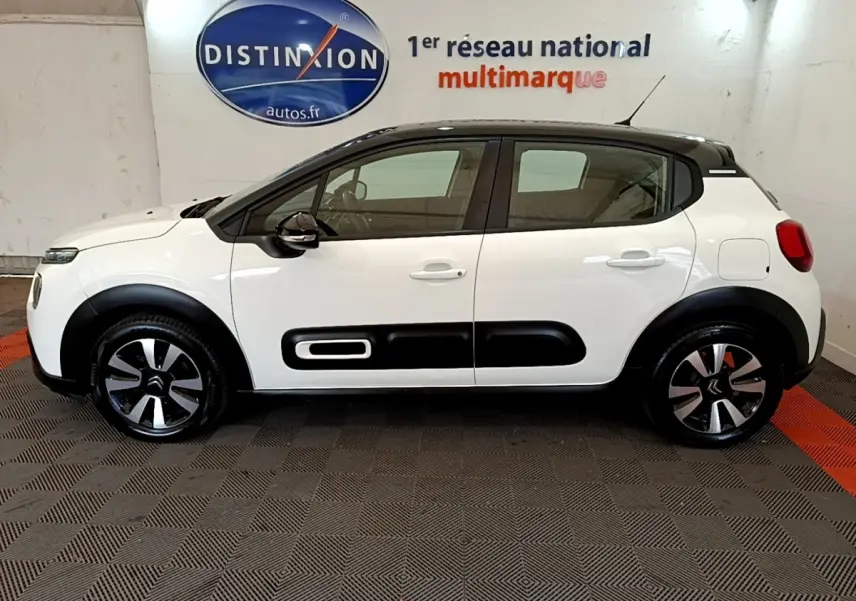Vue de profil côté gauche d'une Citroën C3 blanche avec toit noir et protections latérales noires distinctives.
