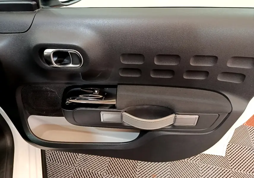 Vue rapprochée de la porte côté conducteur de la Citroën C3 blanche, mettant en valeur la poignée et les commandes de vitre.