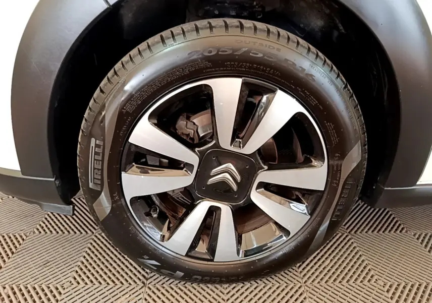 Gros plan sur la roue avant gauche avec jante alliage bicolore et logo Citroën sur une Citroën C3 blanche.