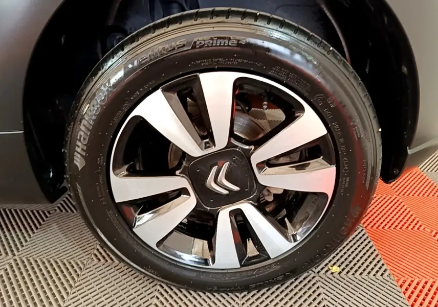 Gros plan sur la jante avant droite noire et argentée avec logo Citroën, sur roue de Citroën C3 blanche.