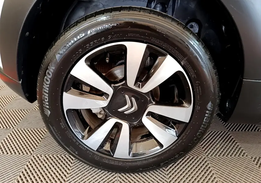 Gros plan sur la roue avant droite d'une Citroën C3 blanche, avec jante alliage bicolore et logo Citroën central.