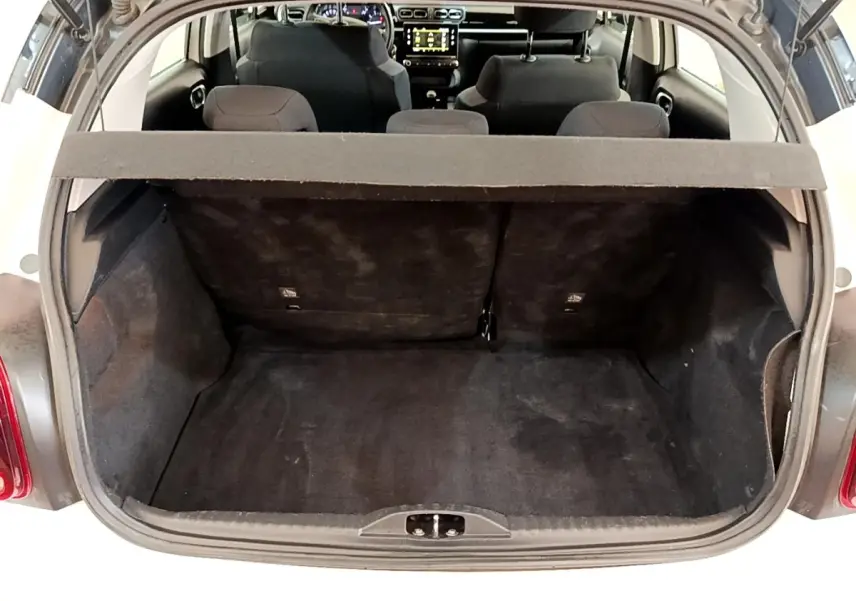 Vue arrière du coffre ouvert d'une Citroën C3 blanche, montrant l'espace de chargement et les sièges arrière.