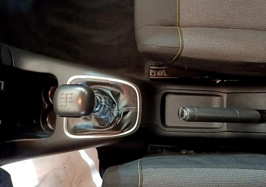 Vue plongeante sur la console centrale de la Citroën C3 blanche, avec levier de vitesse manuel et frein à main entre les sièges.