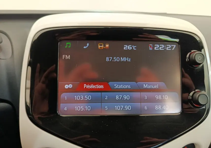 Écran tactile central de la Toyota Aygo 2016 blanc, affichant la radio FM et la température intérieure à 26°C.