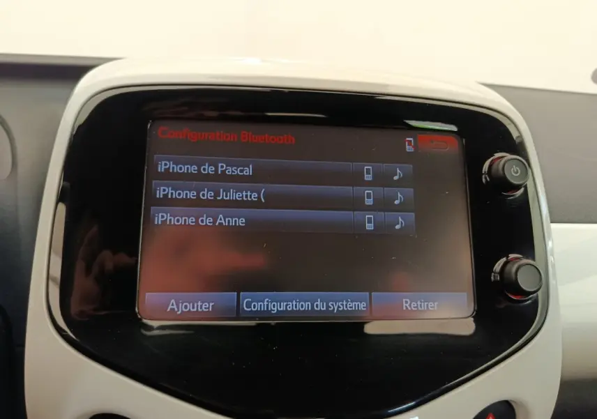 Écran tactile central de la Toyota Aygo blanc, affichant la configuration Bluetooth avec plusieurs iPhones connectés.