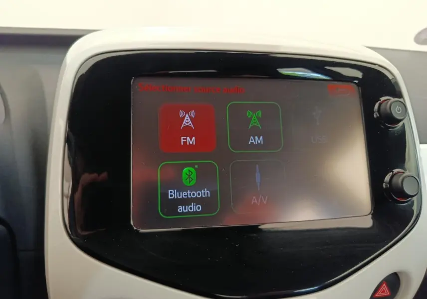Écran tactile central de la Toyota Aygo blanche, affichant les options audio FM, AM et Bluetooth.