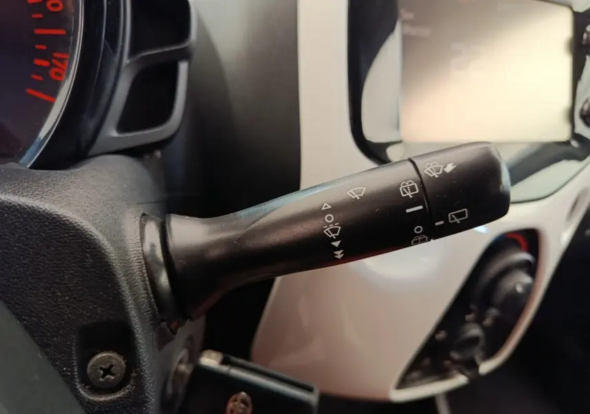 Gros plan sur la commande d’essuie-glaces à gauche du volant dans l’habitacle blanc d’une Toyota Aygo 2016.