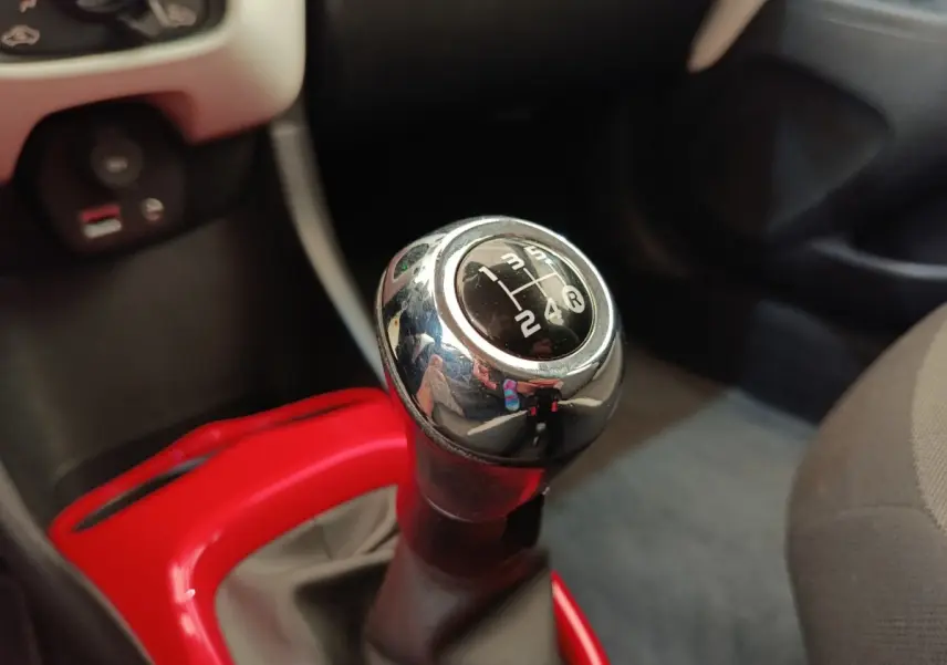 Gros plan sur le levier de vitesses manuel chromé de la Toyota Aygo 2016 avec contour rouge vif du pommeau.