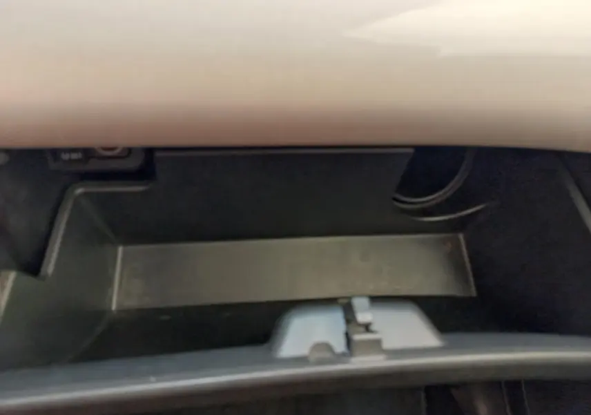 Intérieur du coffre à gants noir de la Toyota Aygo blanche, vue rapprochée sans objets visibles.