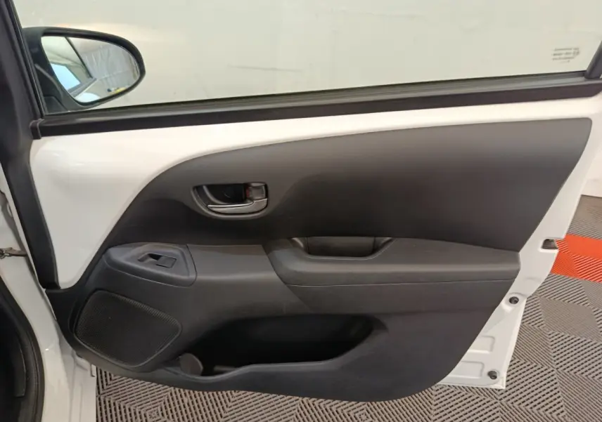 Vue rapprochée de la porte avant gauche blanche de la Toyota Aygo 2016, avec poignée intérieure et commande de vitre.