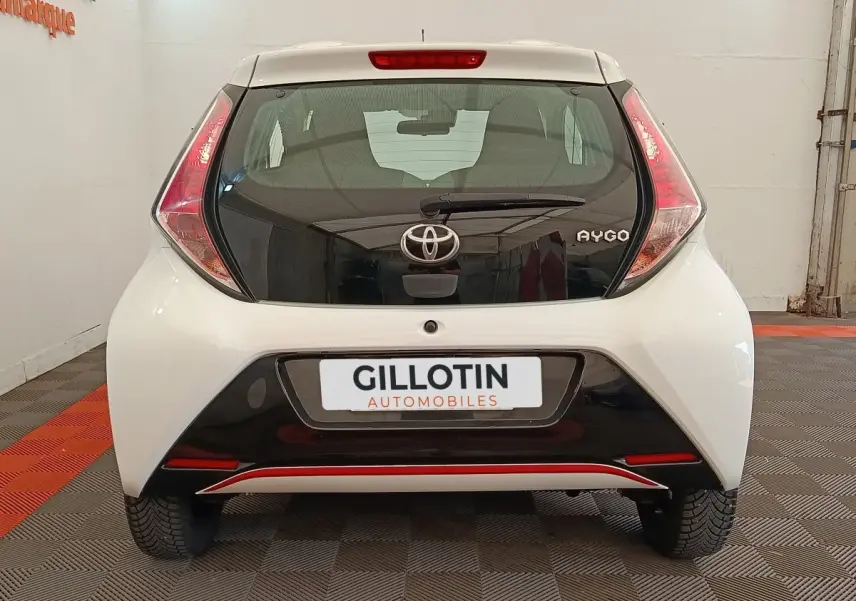 Vue arrière d'une Toyota Aygo blanche 2016 avec hayon noir et feux arrière triangulaires distinctifs.