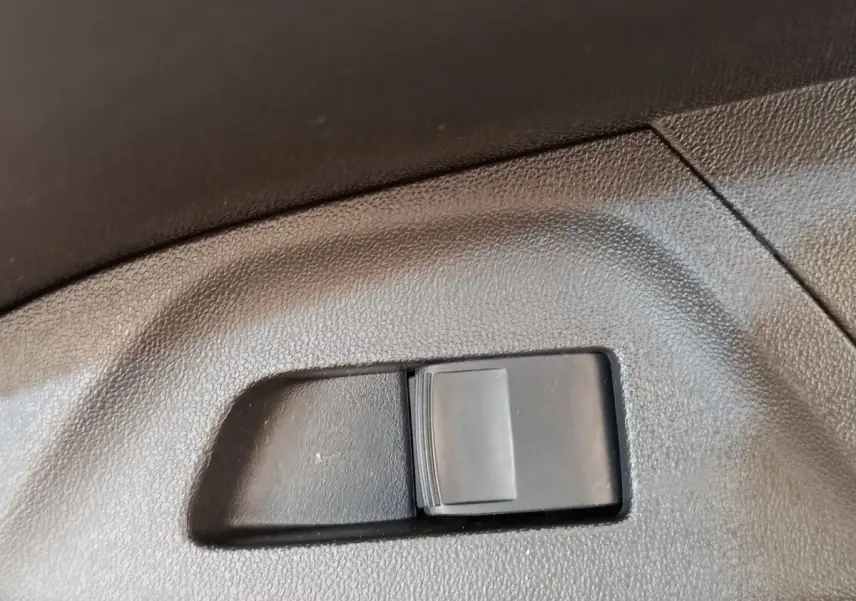 Gros plan sur l'interrupteur de réglage de siège en plastique noir dans l'habitacle d'une Toyota Aygo blanche.