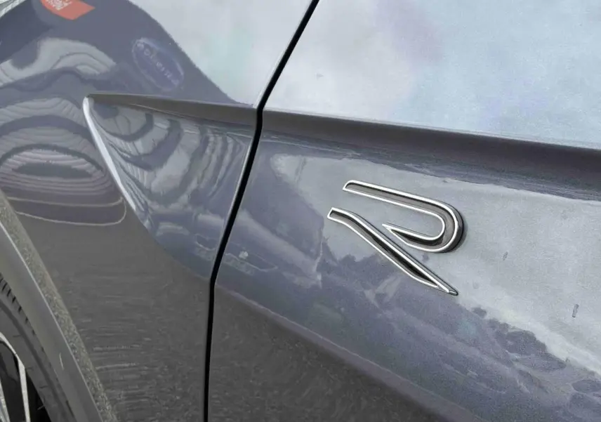 Détail de l'aile avant gauche grise d'un Volkswagen T-Cross avec logo R-Line chromé.