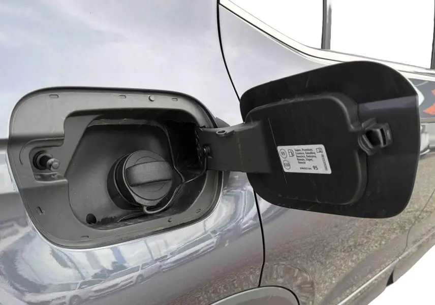 Gros plan sur la trappe à carburant ouverte côté gauche d’un Volkswagen T-Cross gris 2025.