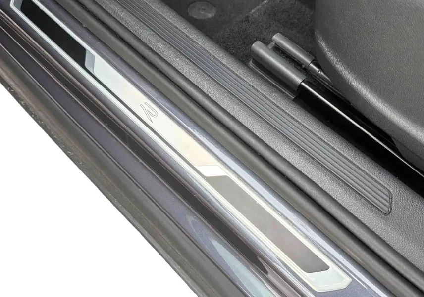 Gros plan sur la plaque de seuil de porte côté conducteur du Volkswagen T-Cross gris, avec logo R visible.