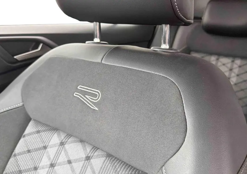 Gros plan sur l'appui-tête avant gris foncé du Volkswagen T-Cross avec logo R brodé, intérieur tissu et cuir.