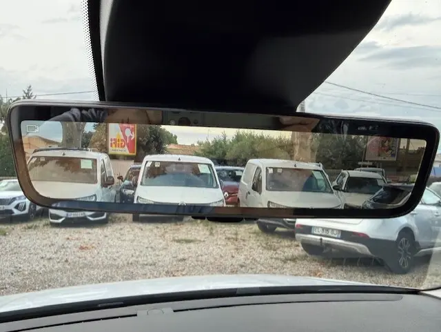 Vue depuis l'intérieur du Citroën Berlingo blanc 2026, reflet du pare-brise arrière montrant plusieurs véhicules blancs stationnés.