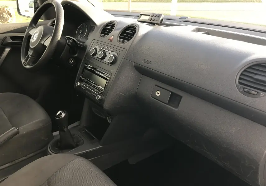 Intérieur noir du Volkswagen Caddy Maxi Van 2015 vu côté passager, tableau de bord avec commandes manuelles et volant à gauche.