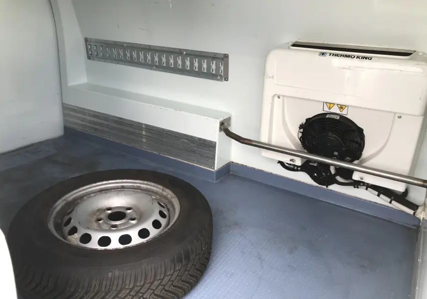 Vue intérieure du compartiment frigorifique blanc du Volkswagen Caddy Maxi Van 2015, avec roue de secours et unité Thermo King.