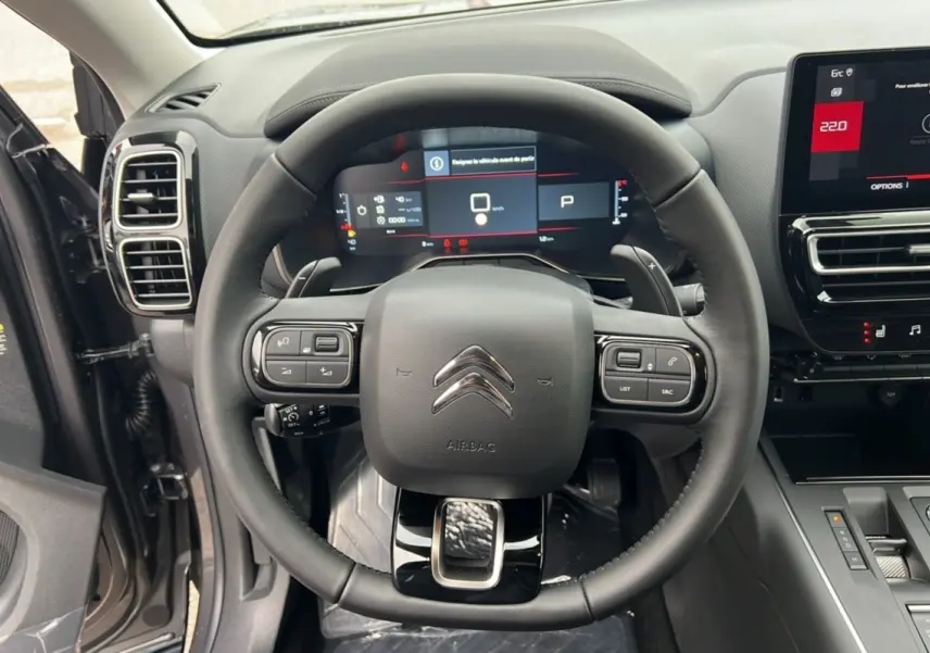 Vue centrée sur le volant et le tableau de bord numérique du Citroën C5 Aircross 2025 gris platinium avec toit noir.