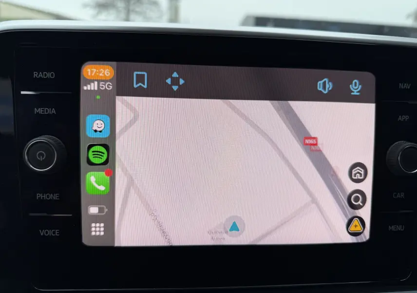 Écran tactile central du Volkswagen T-Roc 2025 affichant la navigation, avec commandes latérales visibles.