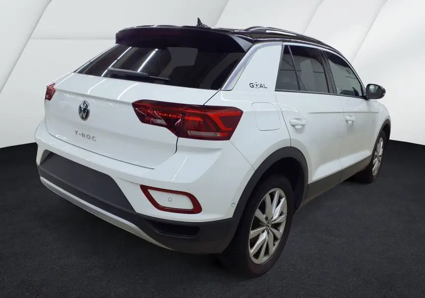 Vue 3/4 arrière droite d’un Volkswagen T-Roc blanc pure avec toit noir, feux arrière LED et jantes alliage.