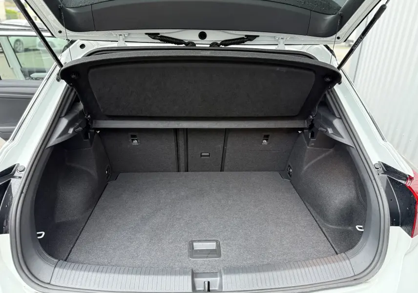 Coffre ouvert vu de l'arrière d'un Volkswagen T-Roc blanc pure toit noir, montrant un espace de chargement propre et spacieux.