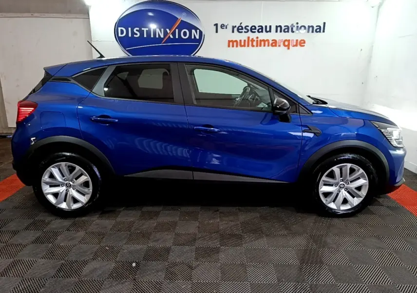 Profil droit d’un Renault Captur bleu 2023 avec jantes alliage et rétroviseurs noirs dans un showroom.